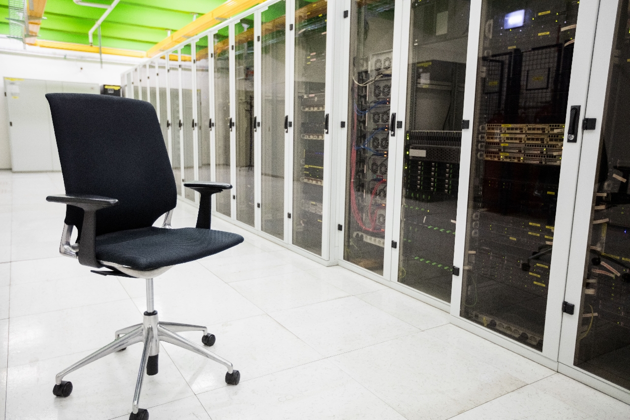 Row of servers behind glass cabinets and an empty office chair in front - fastest host for wordpress