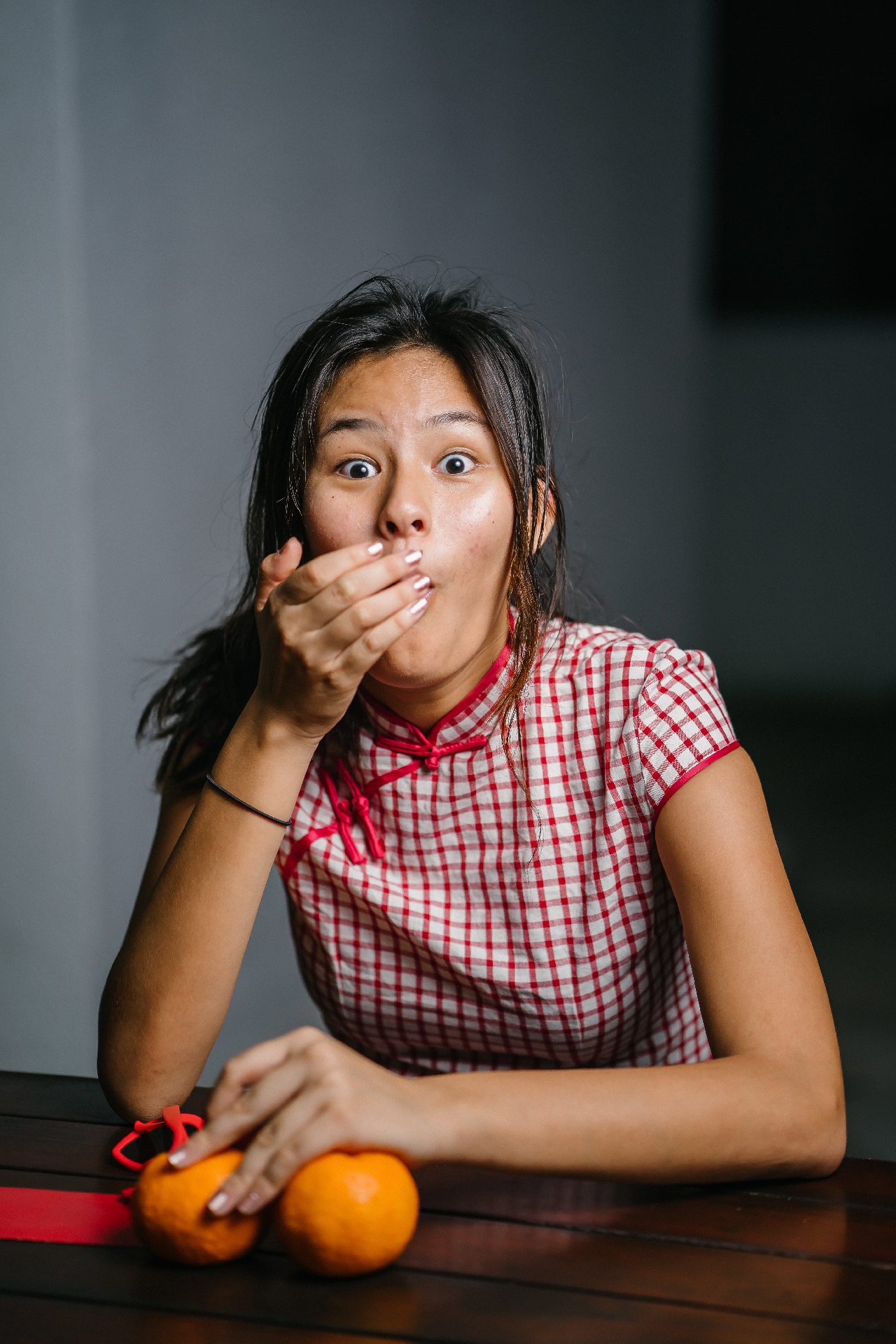 Woman acting shocked looking at the camera with hand over her mouth and eyes open wide.